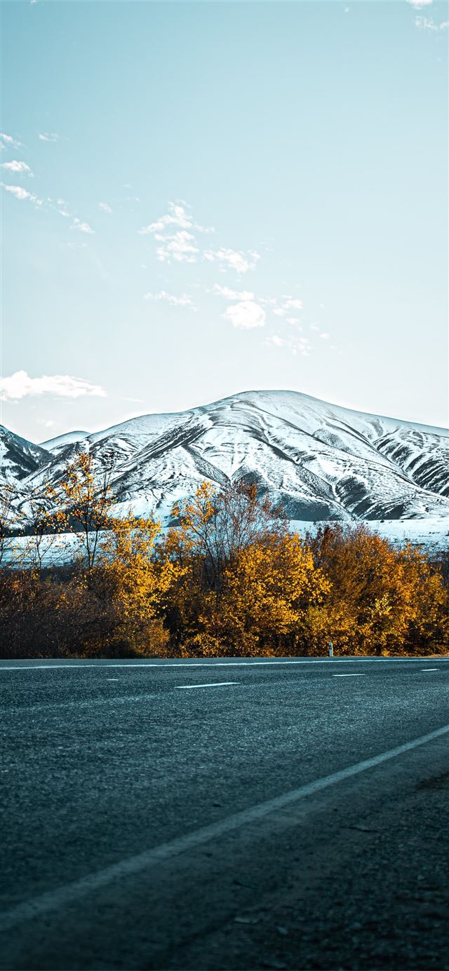 gray asphalt road near snow covered mountain durin... iPhone X wallpaper 