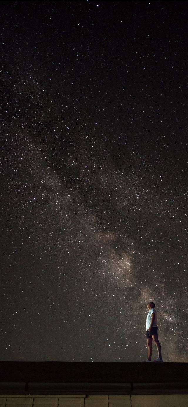 man looking up to Milky Way galaxy at night sky iPhone 11 wallpaper 