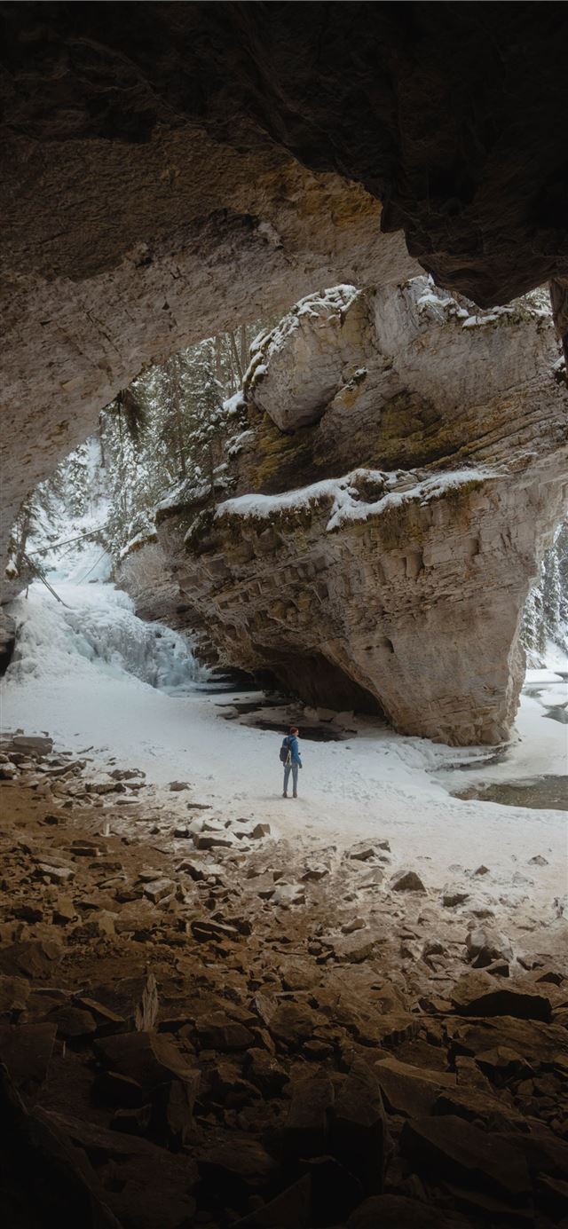 person standing between large rock formation fille... iPhone X wallpaper 