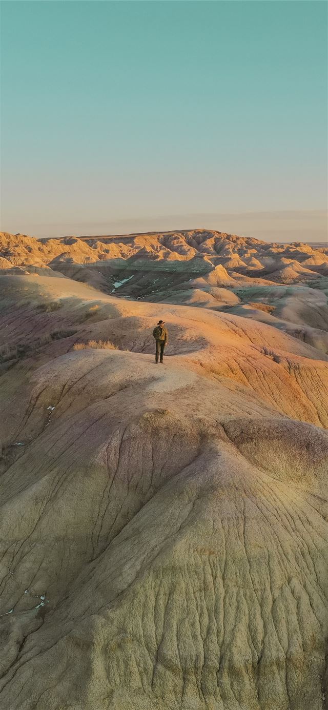 person standing on brown rock formation during day... iPhone 11 wallpaper 