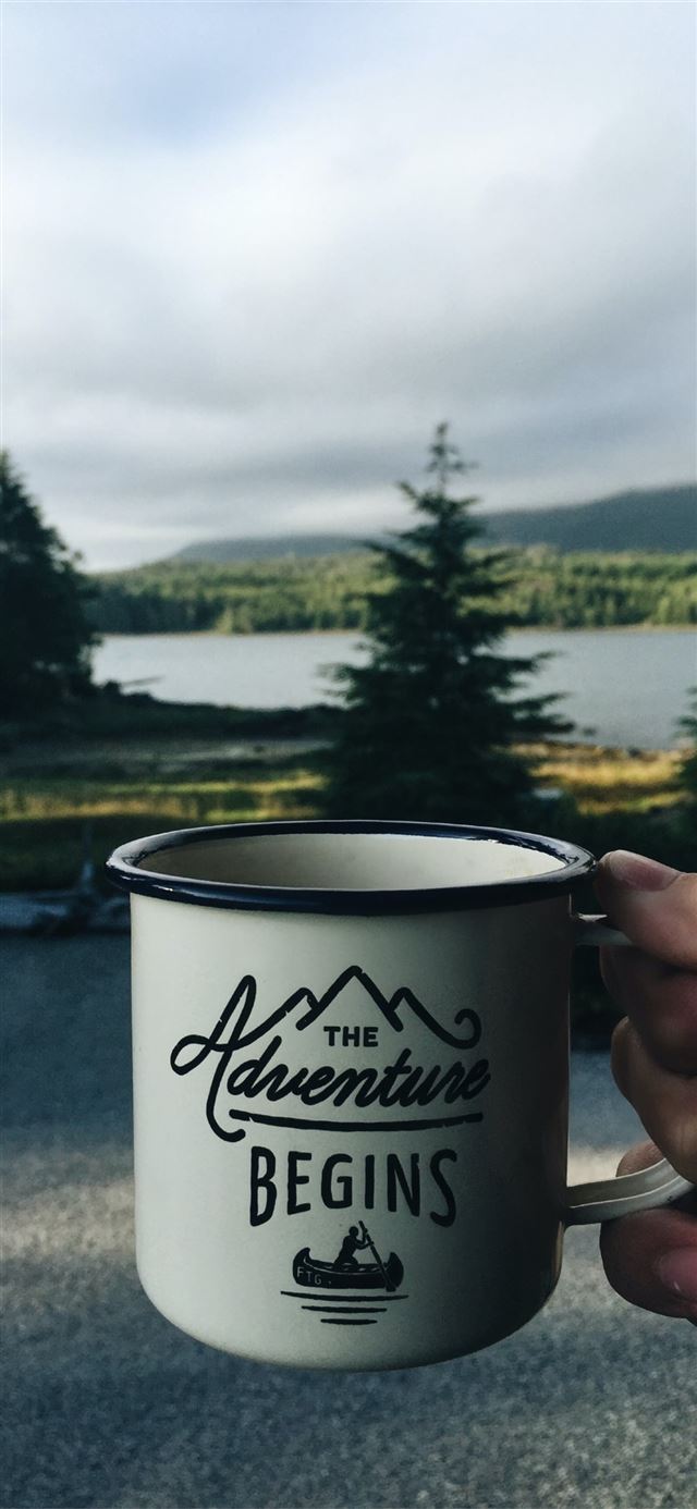 person holding cup with body of water background iPhone X wallpaper 