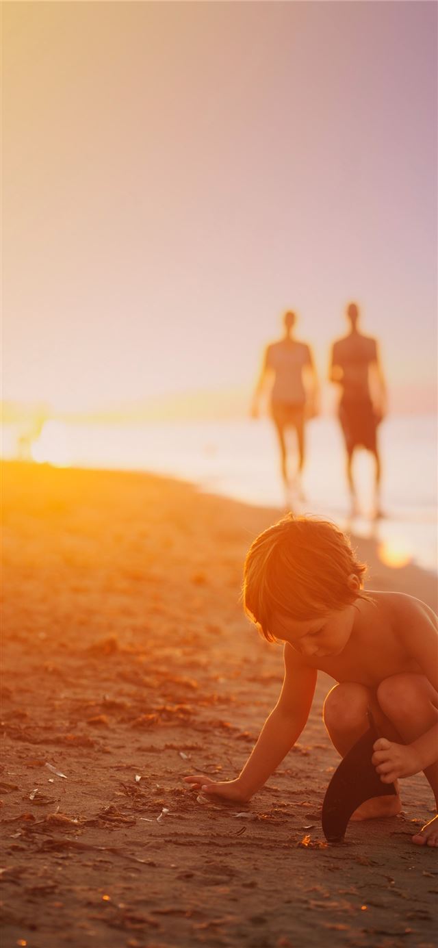 boy playing sand on seashore during sunset iPhone 8 wallpaper 