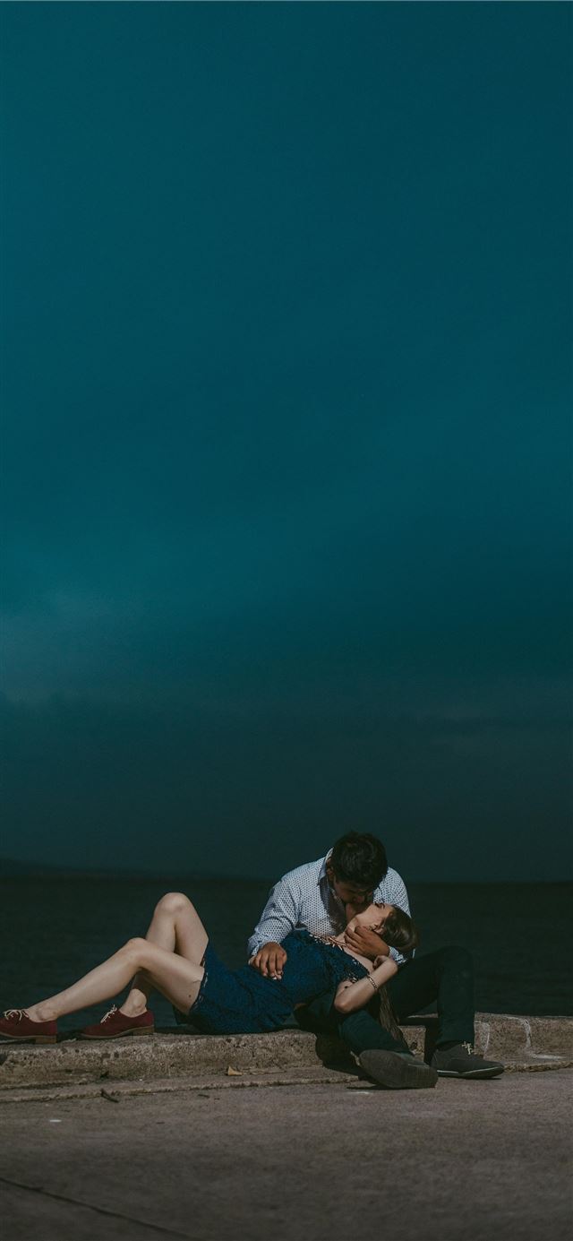 man kissing woman while sitting on railings during... iPhone 8 wallpaper 