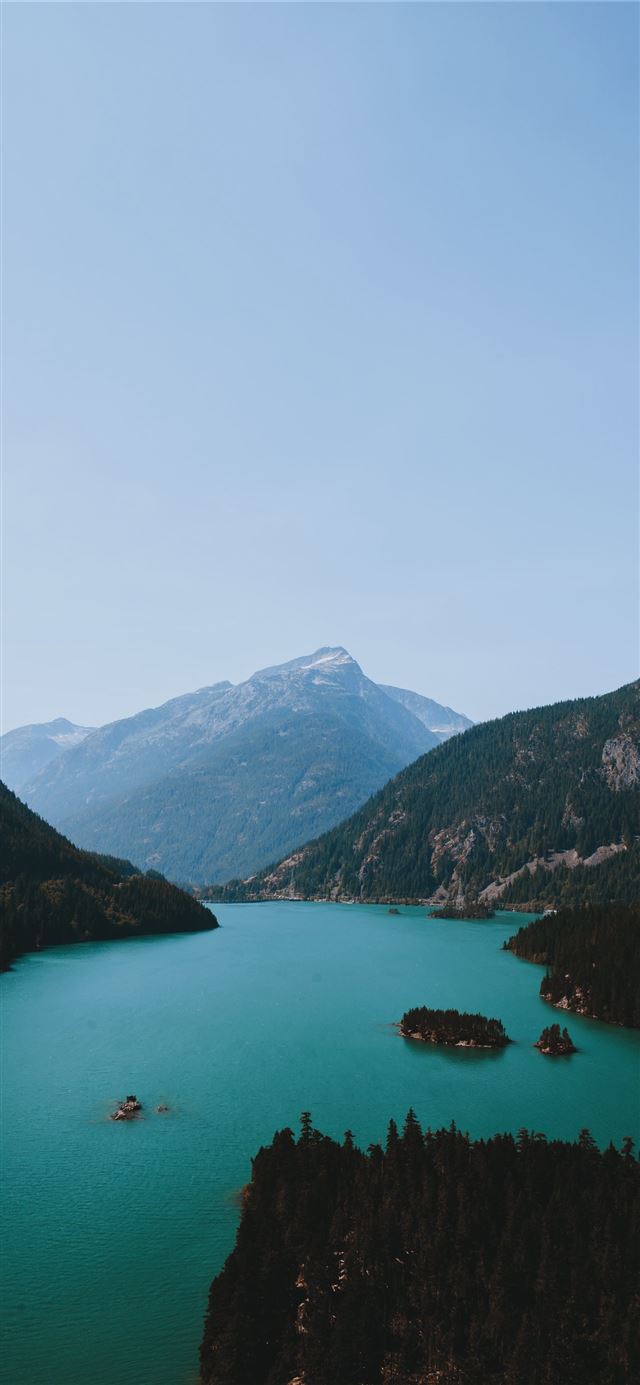 body of water between green and brown mountain ran... iPhone 11 wallpaper 