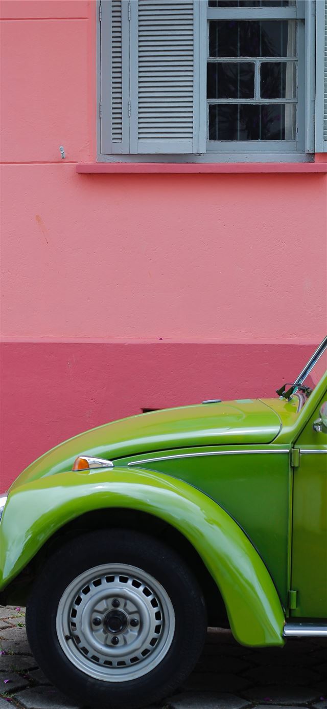 green Volkswagen beetle beside of pink building iPhone 11 wallpaper 