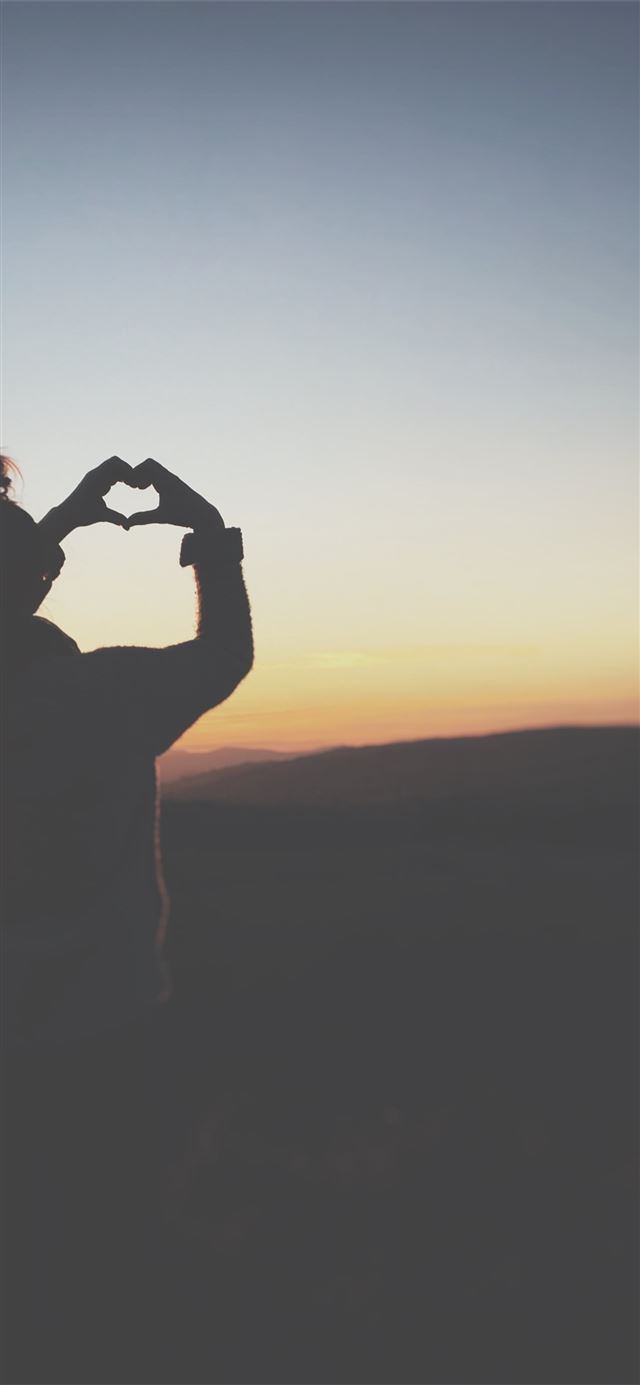 silhouette of a person making heart using her hand... iPhone 11 wallpaper 