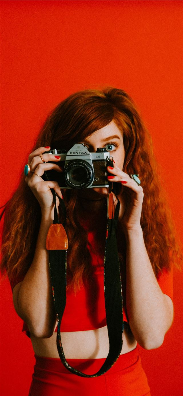 woman in red top and bottoms holding Pentax camera iPhone 11 wallpaper 