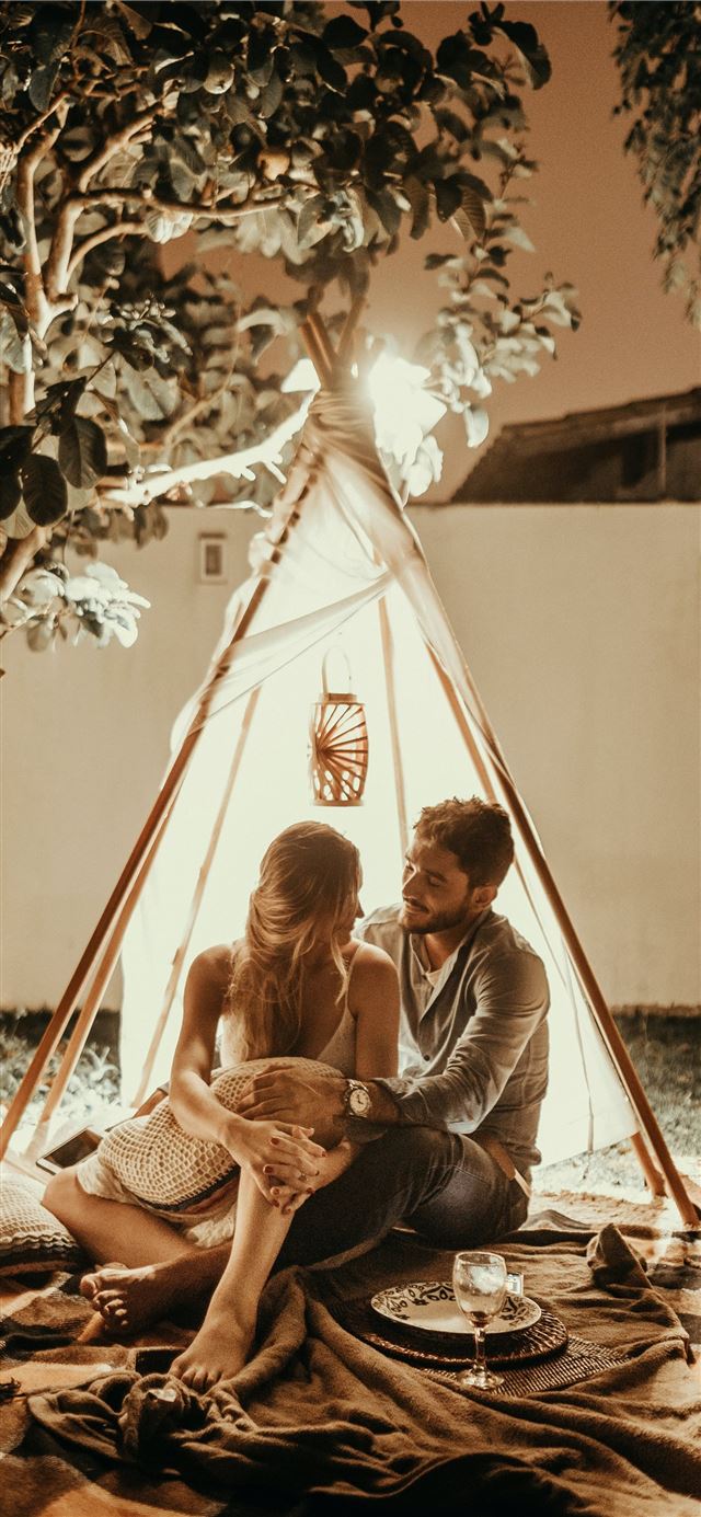 couple sitting inside tepee hut with lights iPhone 11 wallpaper 