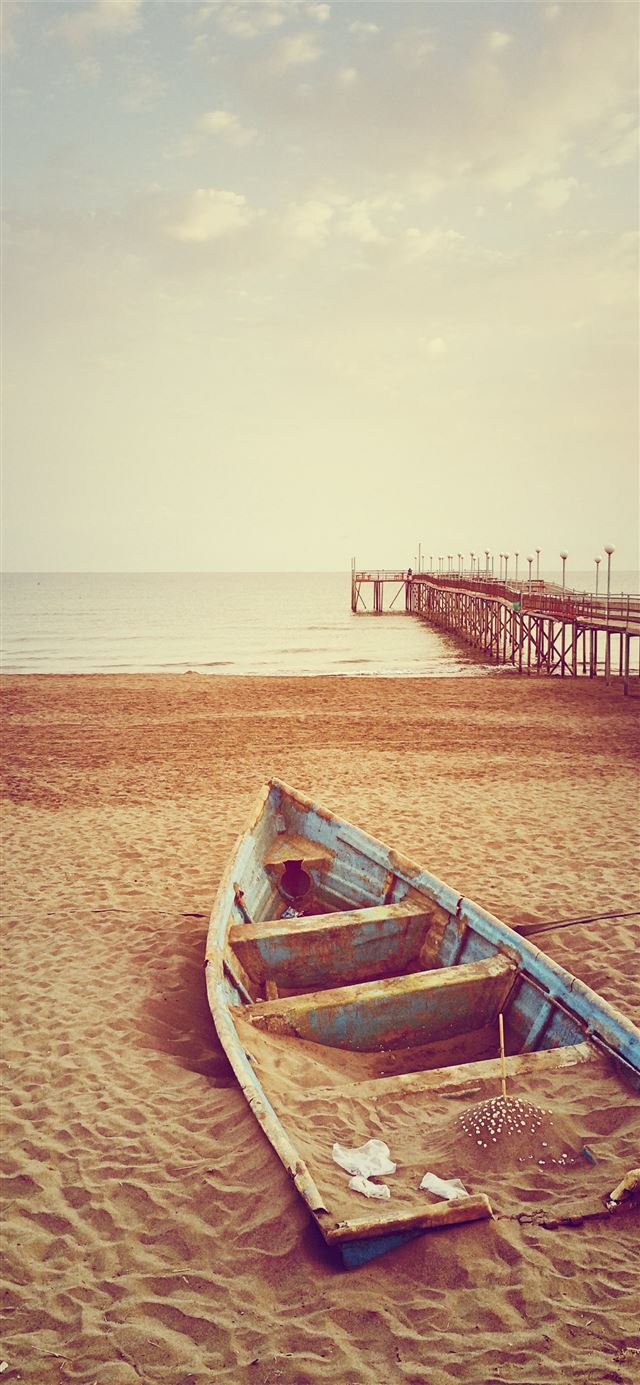 blue canoe boat on brown sand near brown wooden do... iPhone 11 wallpaper 