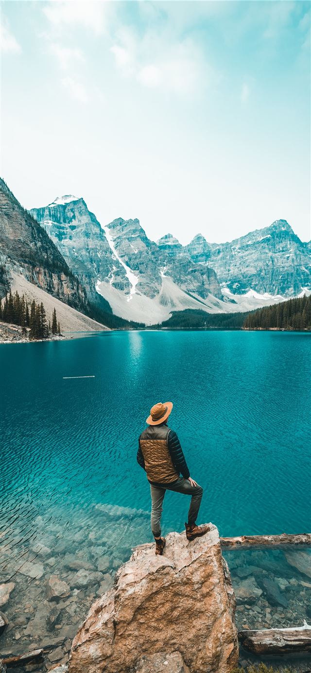 man standing on rock near lake iPhone 11 wallpaper 
