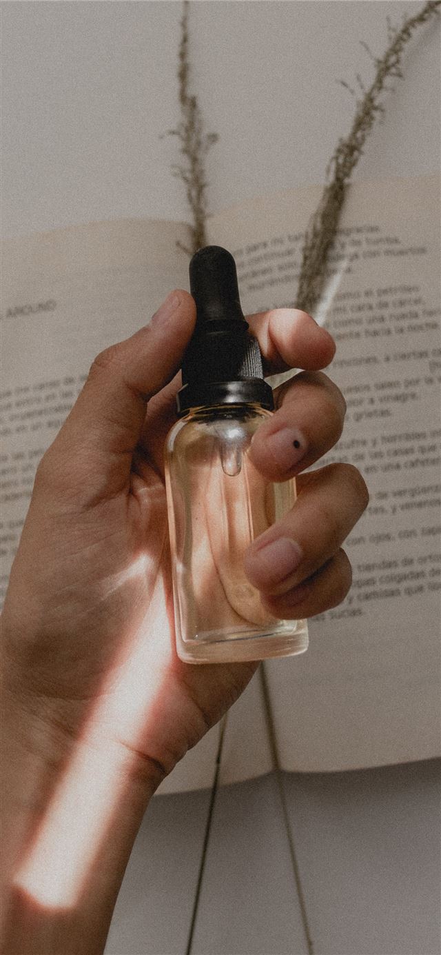 person holding small clear drop bottle iPhone 11 wallpaper 
