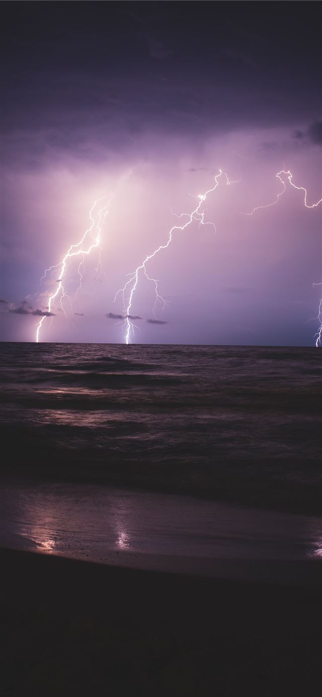 seashore and ocean with lightning during night tim... iPhone 11 wallpaper 