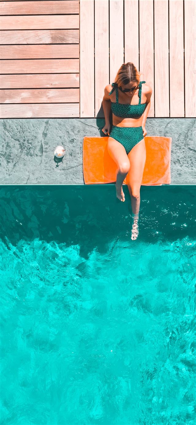 woman lying beside swimming pool during daytime iPhone 8 wallpaper 